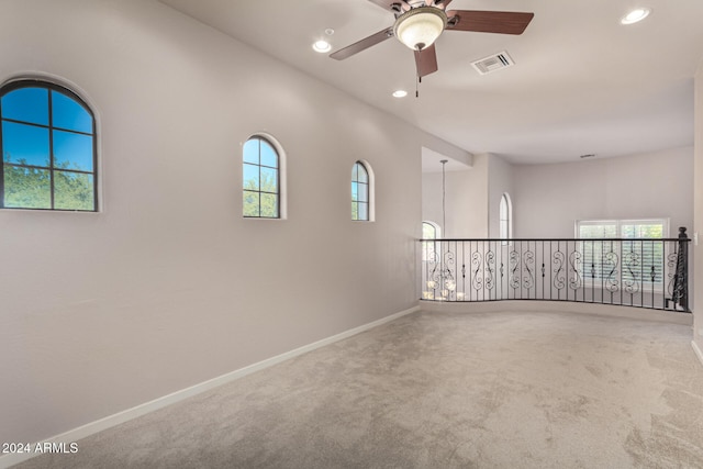 carpeted spare room with plenty of natural light and ceiling fan