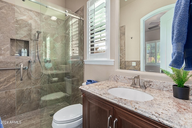 bathroom with walk in shower, ceiling fan, vanity, and toilet