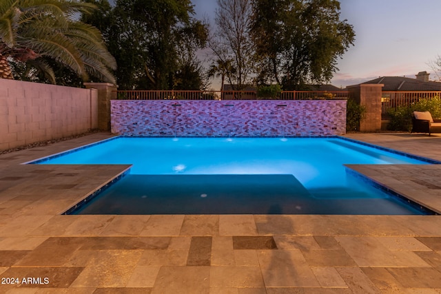 pool at dusk featuring a patio