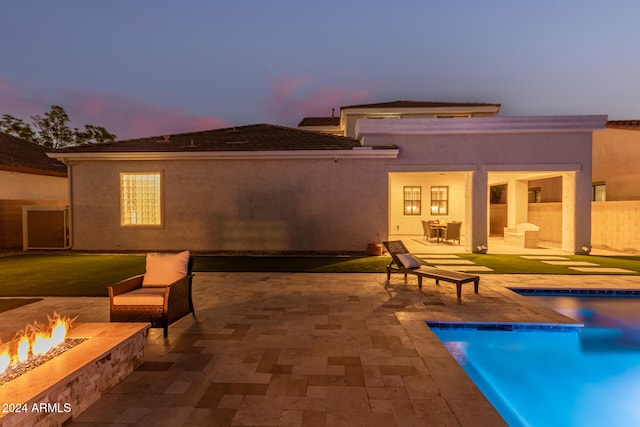 back house at dusk featuring a patio area and an outdoor fire pit