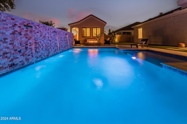 pool at dusk featuring pool water feature