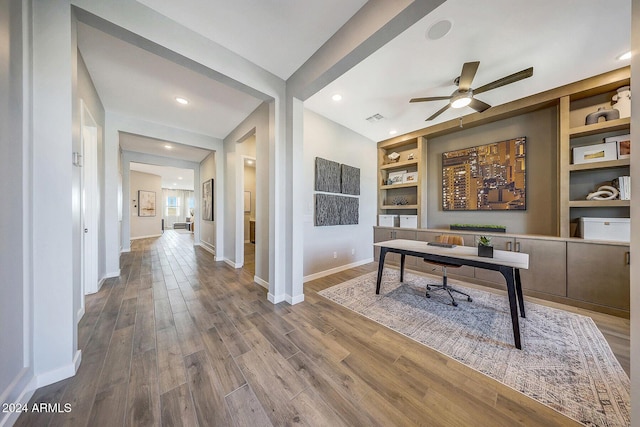 office area featuring wood-type flooring, built in features, and ceiling fan