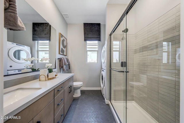 bathroom with a shower with door, vanity, stacked washer / drying machine, and toilet