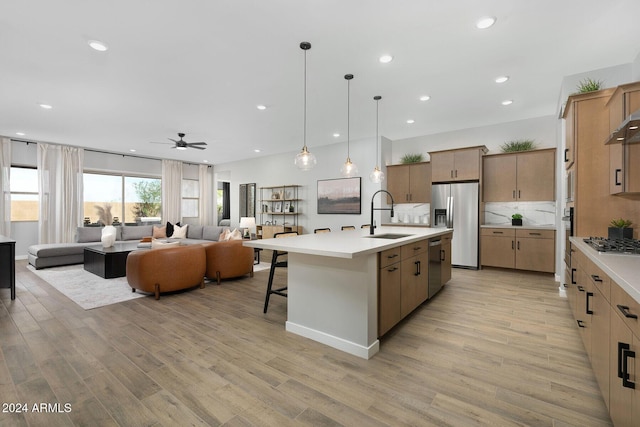 kitchen with a center island with sink, light wood-type flooring, sink, and stainless steel appliances