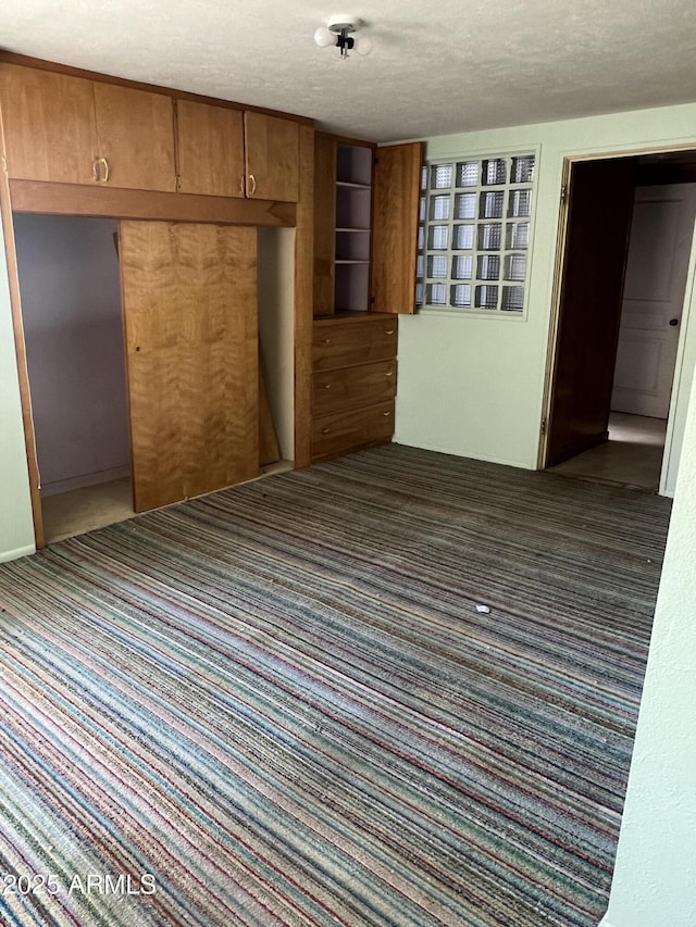 carpeted empty room featuring a textured ceiling