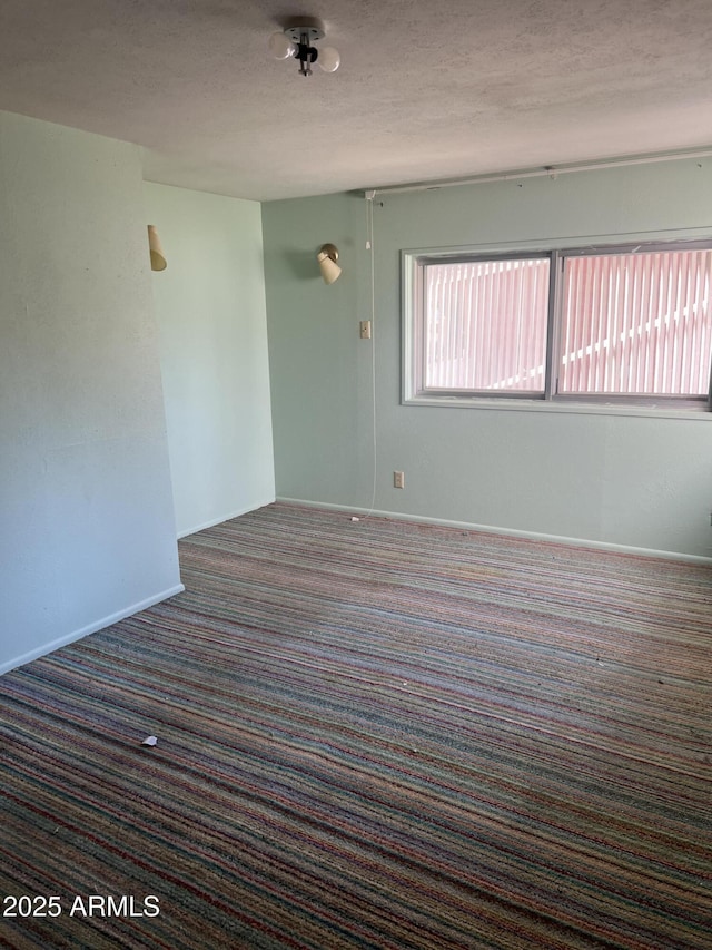 carpeted spare room with a textured ceiling and baseboards