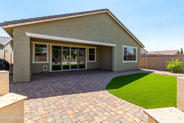 rear view of property with a lawn and a patio area