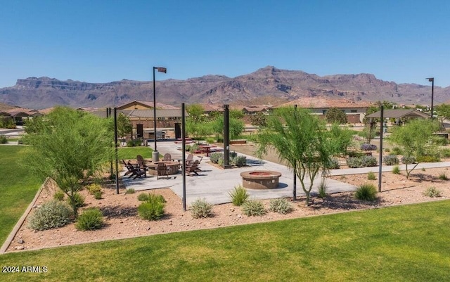 view of community featuring a mountain view, a patio area, an outdoor fire pit, and a yard