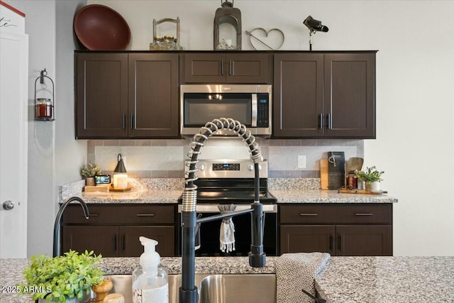 kitchen featuring tasteful backsplash, light stone counters, and dark brown cabinets