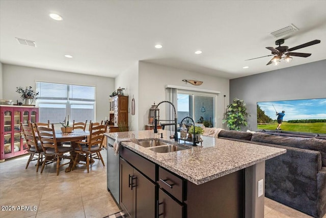 kitchen featuring a healthy amount of sunlight, sink, a kitchen island with sink, and dark brown cabinetry