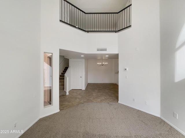 interior space with carpet floors, visible vents, a high ceiling, a chandelier, and stairs