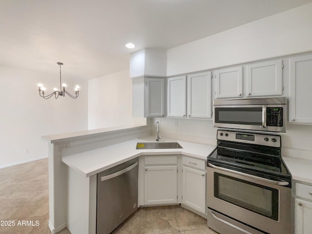 kitchen featuring decorative light fixtures, light countertops, appliances with stainless steel finishes, a sink, and a peninsula