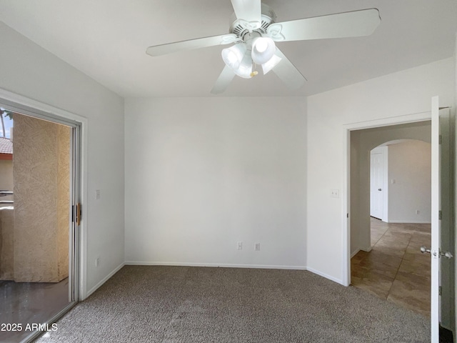 carpeted spare room featuring arched walkways, ceiling fan, and baseboards