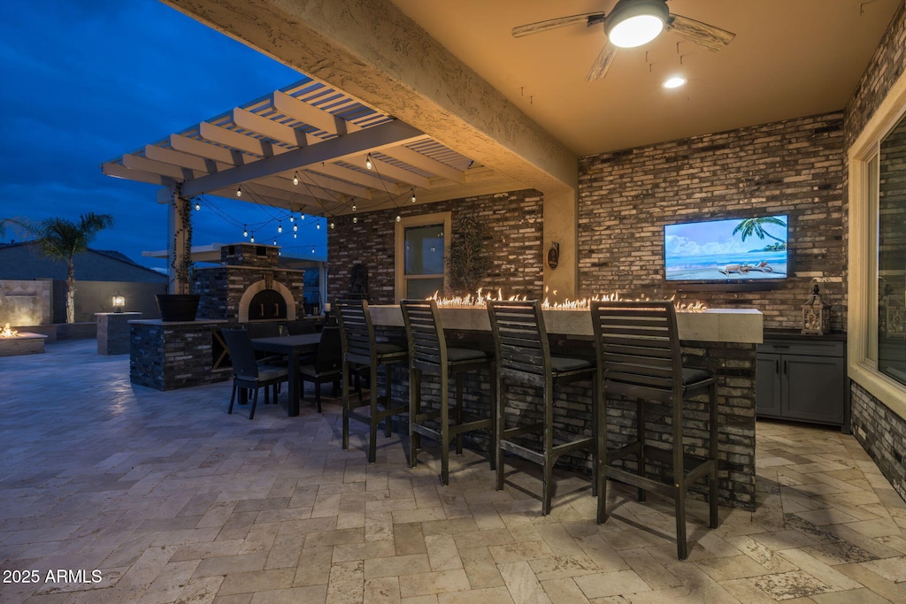 view of patio / terrace featuring ceiling fan, exterior bar, exterior kitchen, and an outdoor fireplace