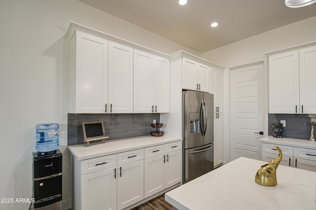 kitchen featuring white cabinetry, stainless steel fridge, dark hardwood / wood-style flooring, light stone countertops, and decorative backsplash