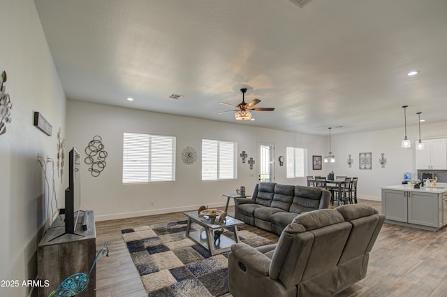 living room featuring sink, ceiling fan, and light wood-type flooring