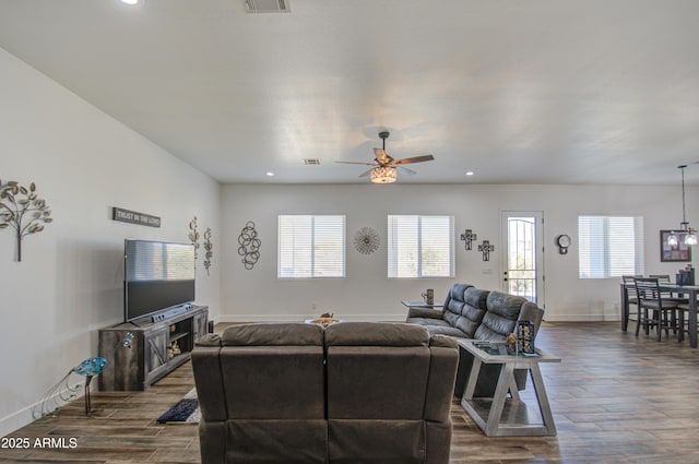 living room featuring wood-type flooring, ceiling fan with notable chandelier, and a wealth of natural light