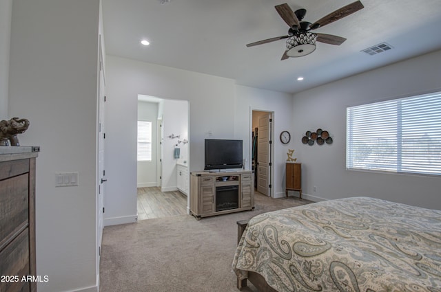 bedroom featuring light carpet, ceiling fan, and ensuite bathroom