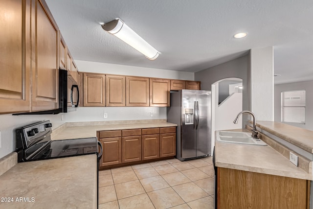 kitchen featuring light tile patterned floors, a textured ceiling, black appliances, and sink