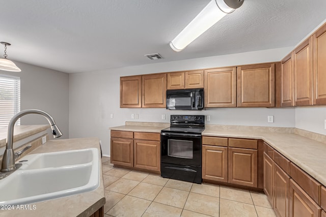 kitchen with light tile patterned flooring, black appliances, sink, and pendant lighting