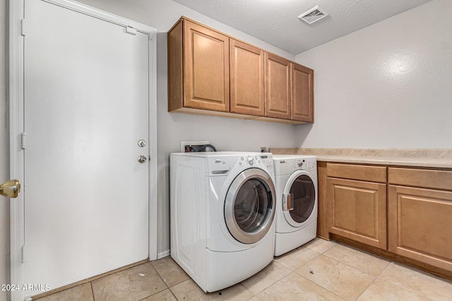 laundry area with independent washer and dryer, a textured ceiling, light tile patterned floors, and cabinets