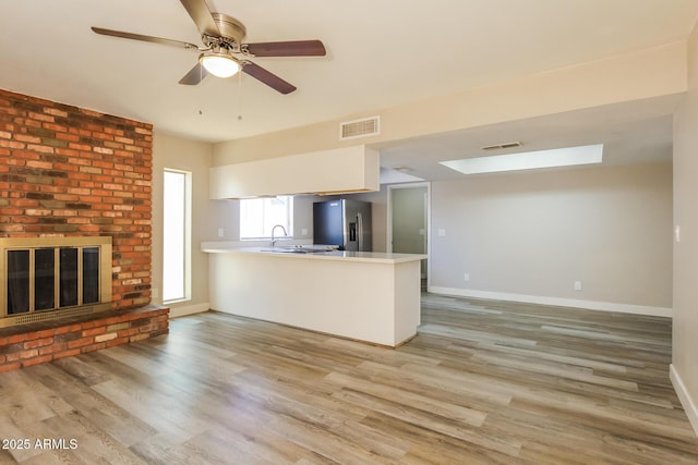 9622 N 35th Ln, Phoenix, AZ 85051 - kitchen with stainless steel refrigerator with ice dispenser, a peninsula, a skylight, light wood-style flooring, and open floor plan