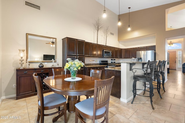 dining area with sink, light tile patterned floors, and a high ceiling