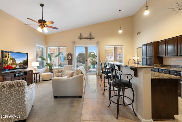 tiled living room with ceiling fan, sink, and high vaulted ceiling