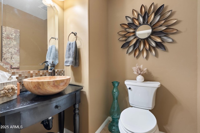 bathroom with toilet, sink, and backsplash