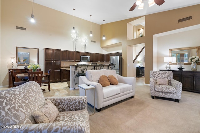 carpeted living room featuring a towering ceiling and ceiling fan