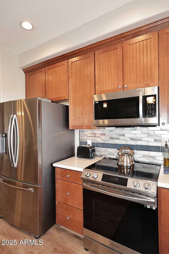 kitchen with decorative backsplash, stainless steel appliances, and light hardwood / wood-style flooring