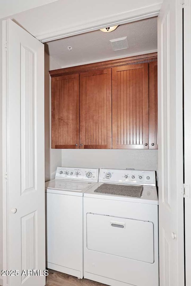 laundry room with cabinets, light hardwood / wood-style flooring, and washing machine and clothes dryer