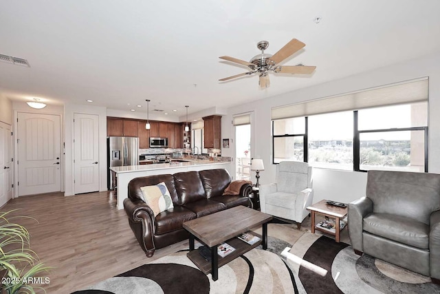 living room featuring ceiling fan and light hardwood / wood-style flooring