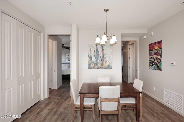 dining space with ceiling fan with notable chandelier and dark hardwood / wood-style flooring