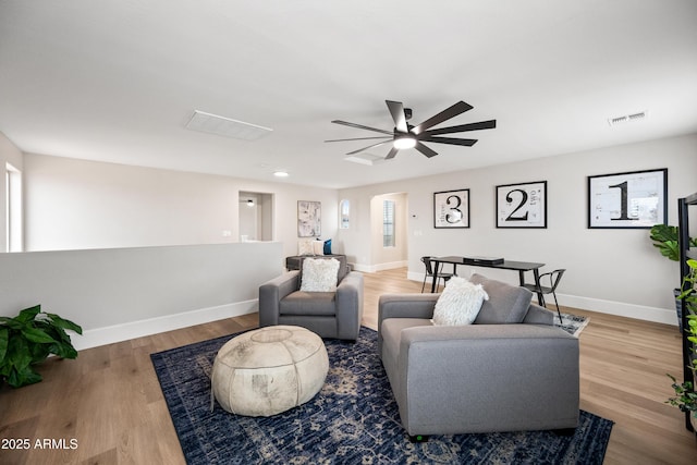 living area featuring baseboards, visible vents, arched walkways, and wood finished floors