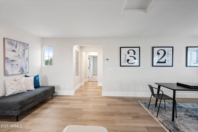 living room featuring attic access, light wood-style flooring, and baseboards