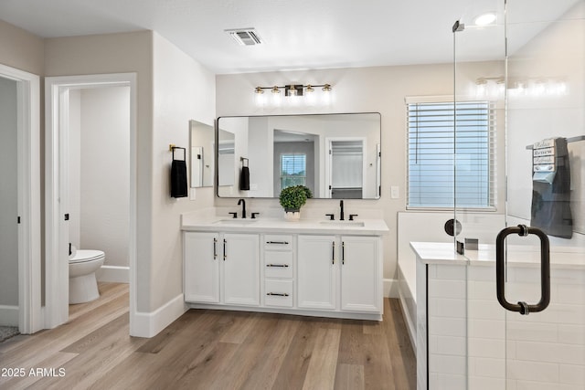 bathroom with toilet, visible vents, a sink, and wood finished floors