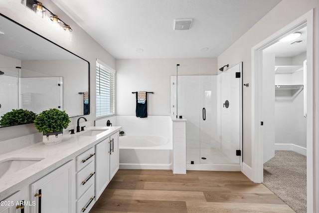 bathroom with double vanity, a garden tub, a shower stall, and a sink