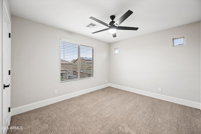 carpeted spare room featuring a ceiling fan, visible vents, and baseboards