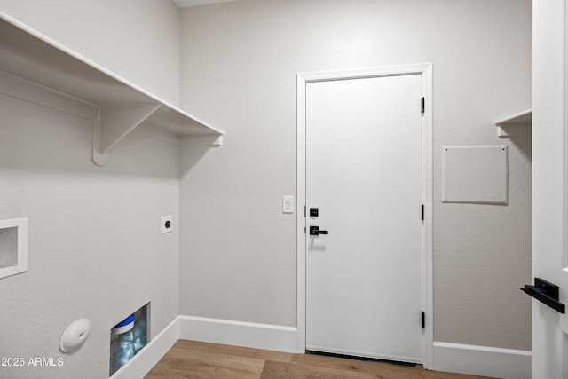 clothes washing area with laundry area, electric dryer hookup, baseboards, and wood finished floors