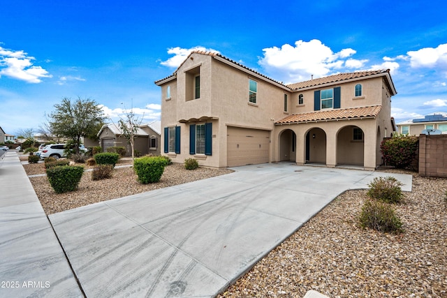 mediterranean / spanish-style house with concrete driveway, fence, an attached garage, and stucco siding