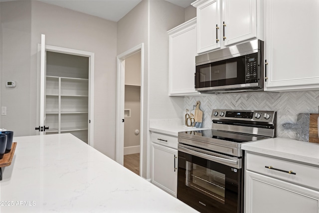 kitchen featuring light stone counters, appliances with stainless steel finishes, backsplash, and white cabinetry