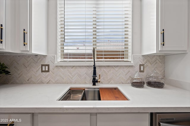 kitchen featuring white cabinetry, decorative backsplash, and a sink