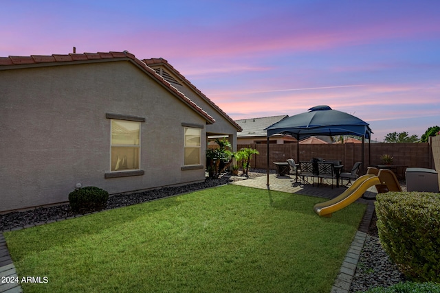 yard at dusk featuring a patio and a gazebo