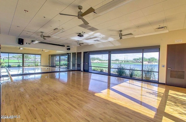 empty room featuring a healthy amount of sunlight, light hardwood / wood-style floors, a water view, and ceiling fan