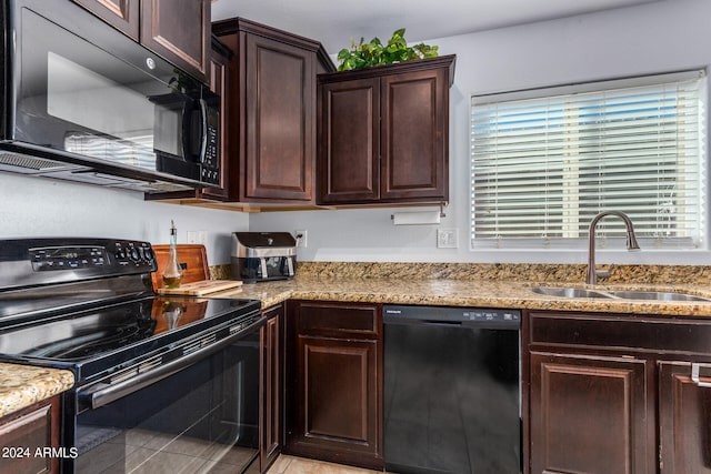 kitchen featuring black appliances, dark brown cabinetry, sink, and light tile patterned floors