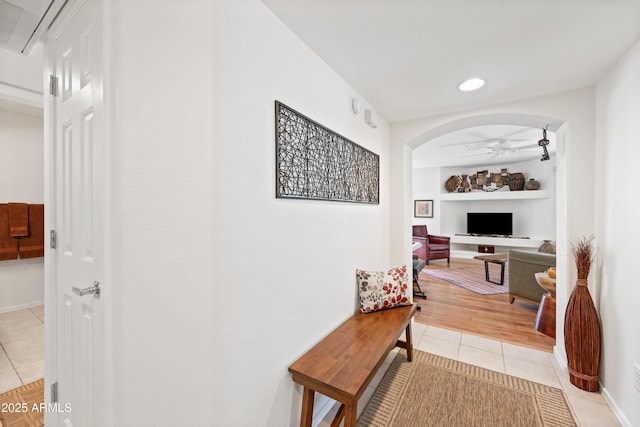 hallway featuring recessed lighting, arched walkways, baseboards, and light tile patterned floors
