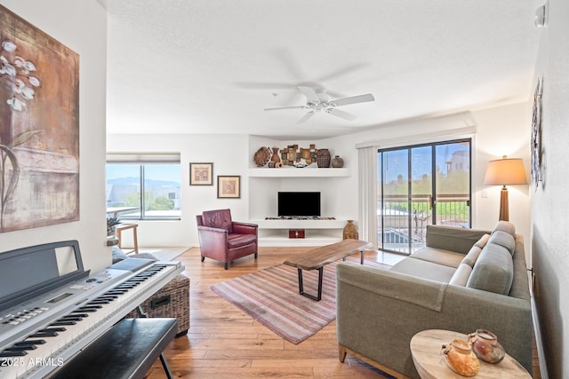 living room featuring wood-type flooring, a ceiling fan, and a wealth of natural light