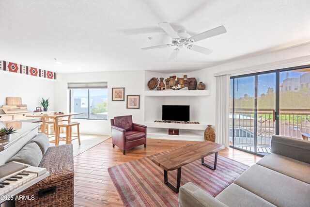 living room featuring light wood-style floors, ceiling fan, and a wealth of natural light