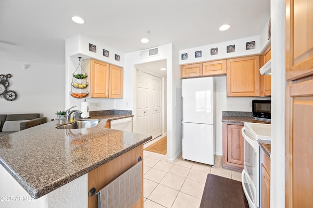 kitchen featuring visible vents, a peninsula, light brown cabinets, white appliances, and a sink